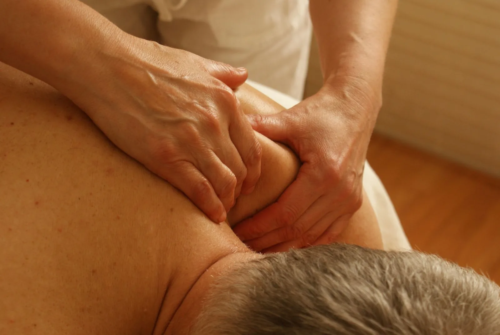 Two hands working a man's shoulder muscle