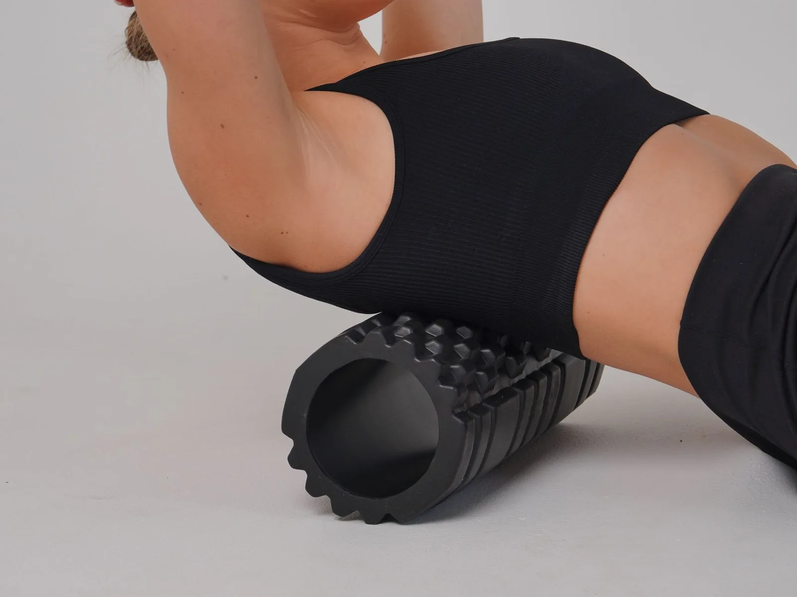 A woman using a foam roller to stretch and release her back during a workout.