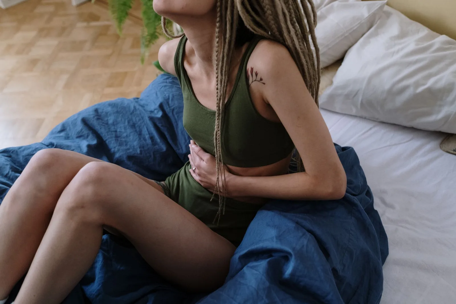 Woman sitting on a bed holding her stomach