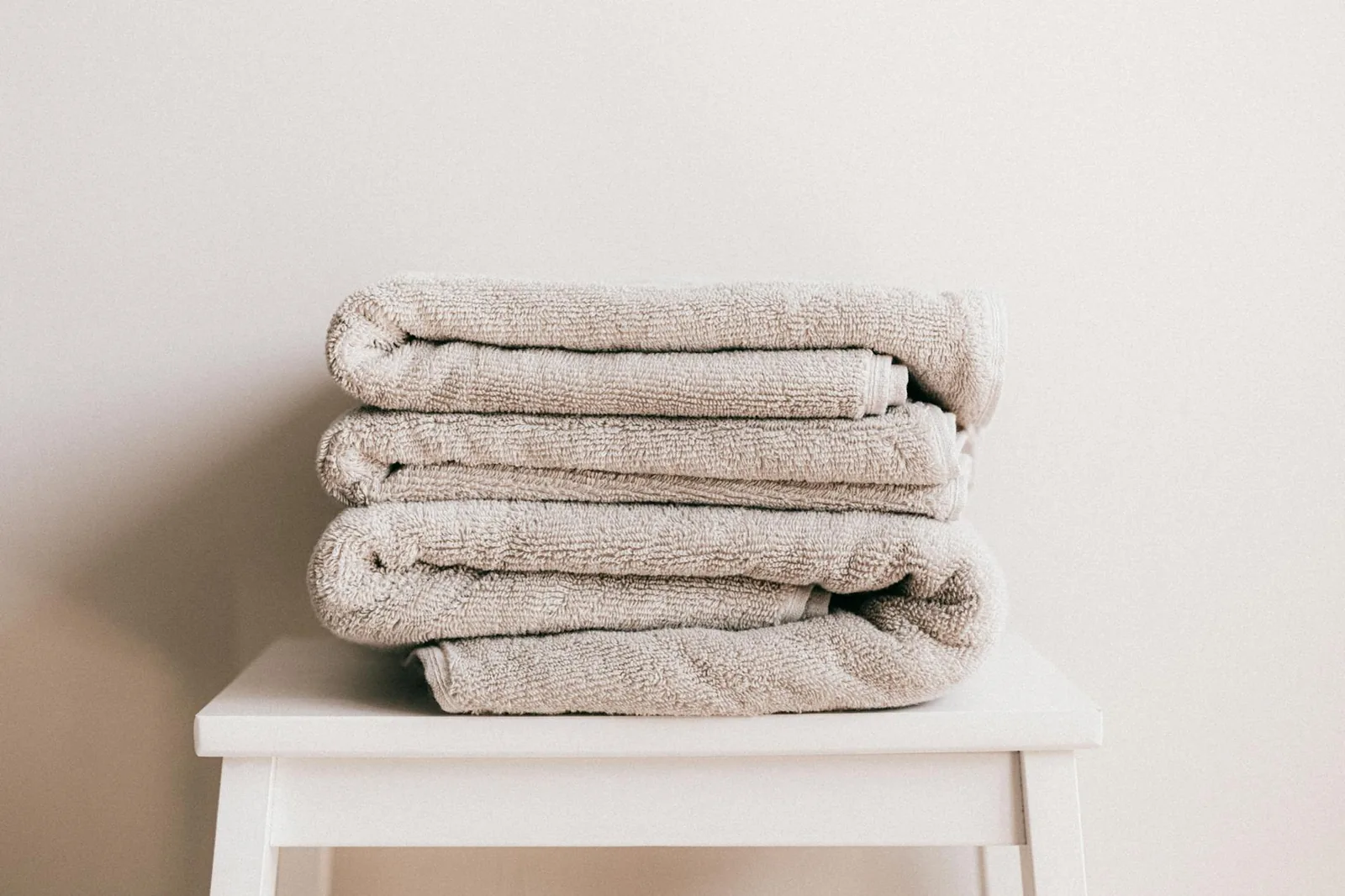A stack of soft, clean, light-beige folded towels representing the linen inventory a mobile therapist cycles through every week.