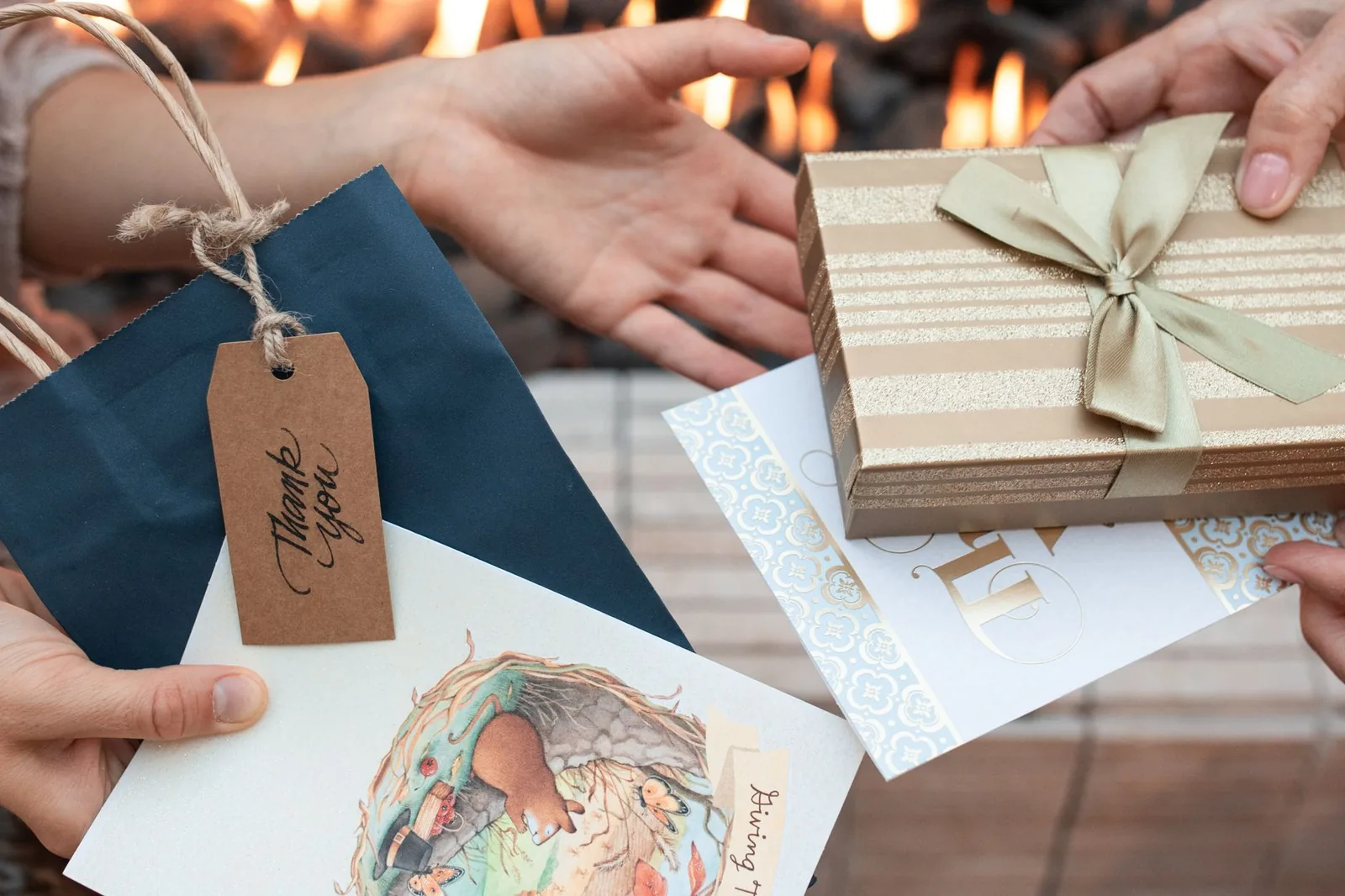 Close-up of hands exchanging a wrapped gift and card, representing a massage gift certificate given between friends.