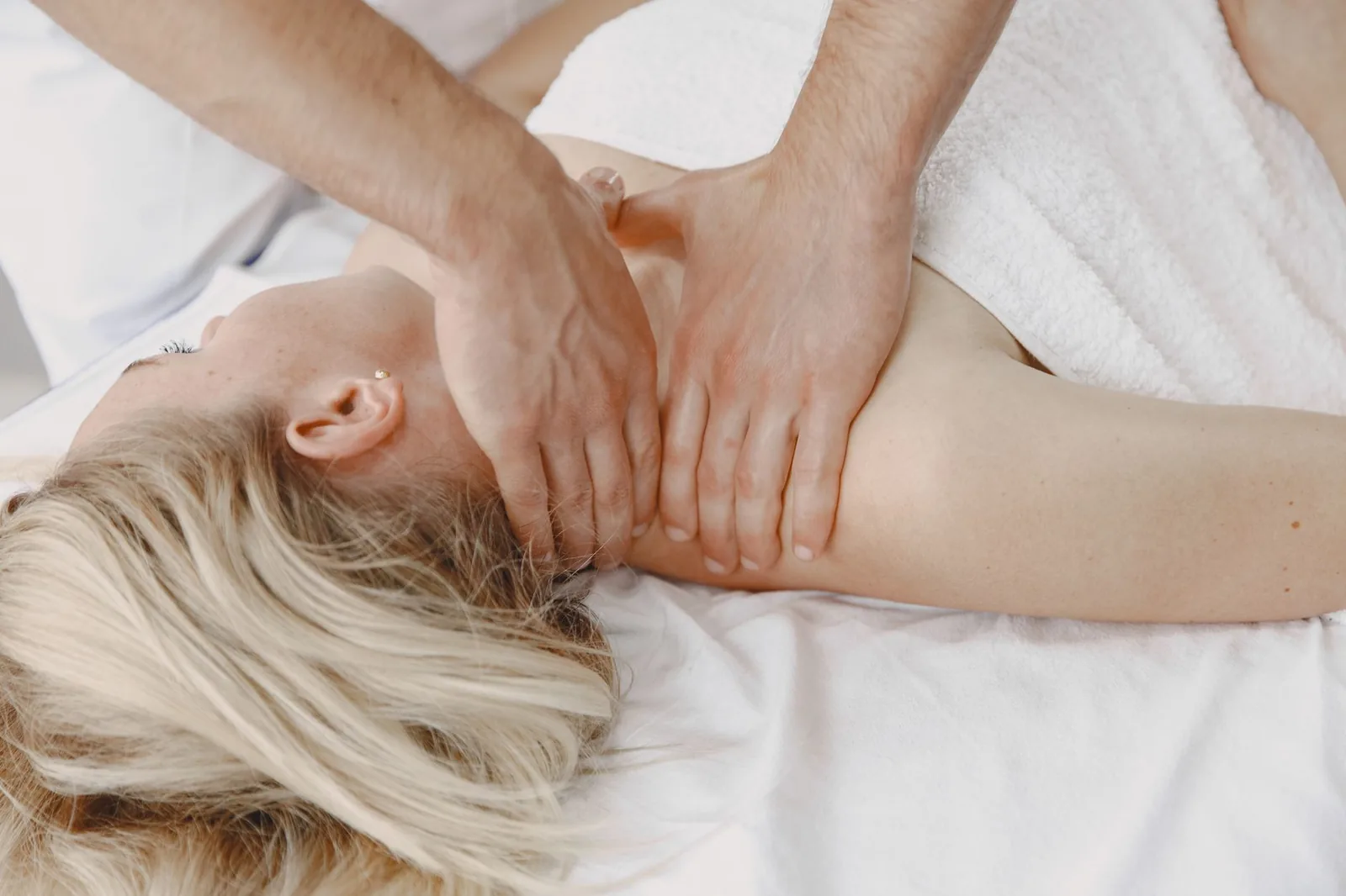 Therapist's hands working the neck and shoulder of a client